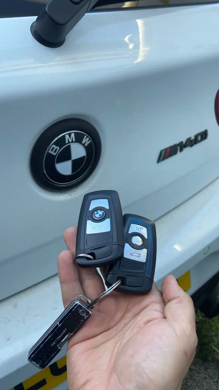BMW M140i with its two keys held in front of the boot badge — hot hatches like this are regular targets for keyless theft